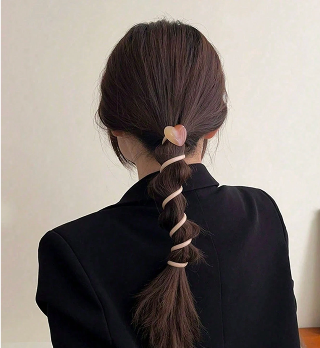 Person with a ponytail using a hair tie against a plain background
